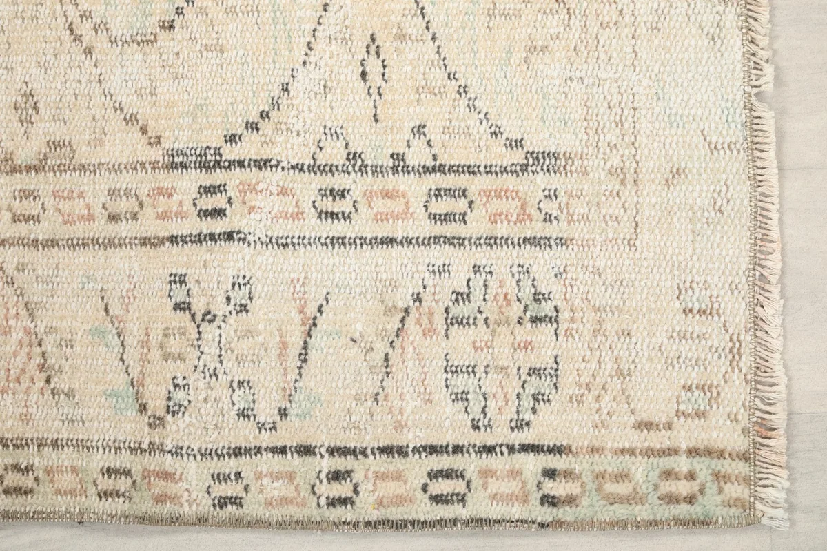 Detailed shot of the rug's short end, showing the geometric border and fringe.