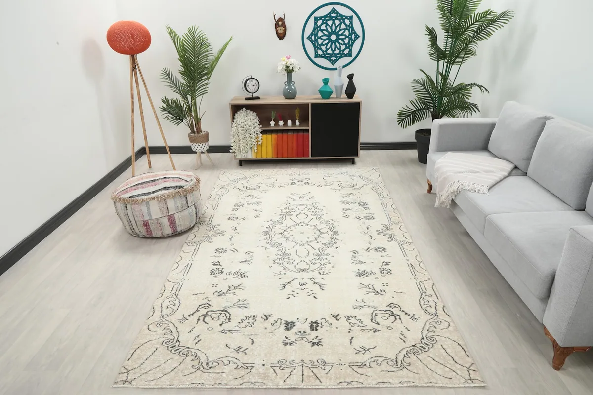 Ivory and charcoal vintage Anatolian rug in a modern living room setting with a gray sofa and plants.