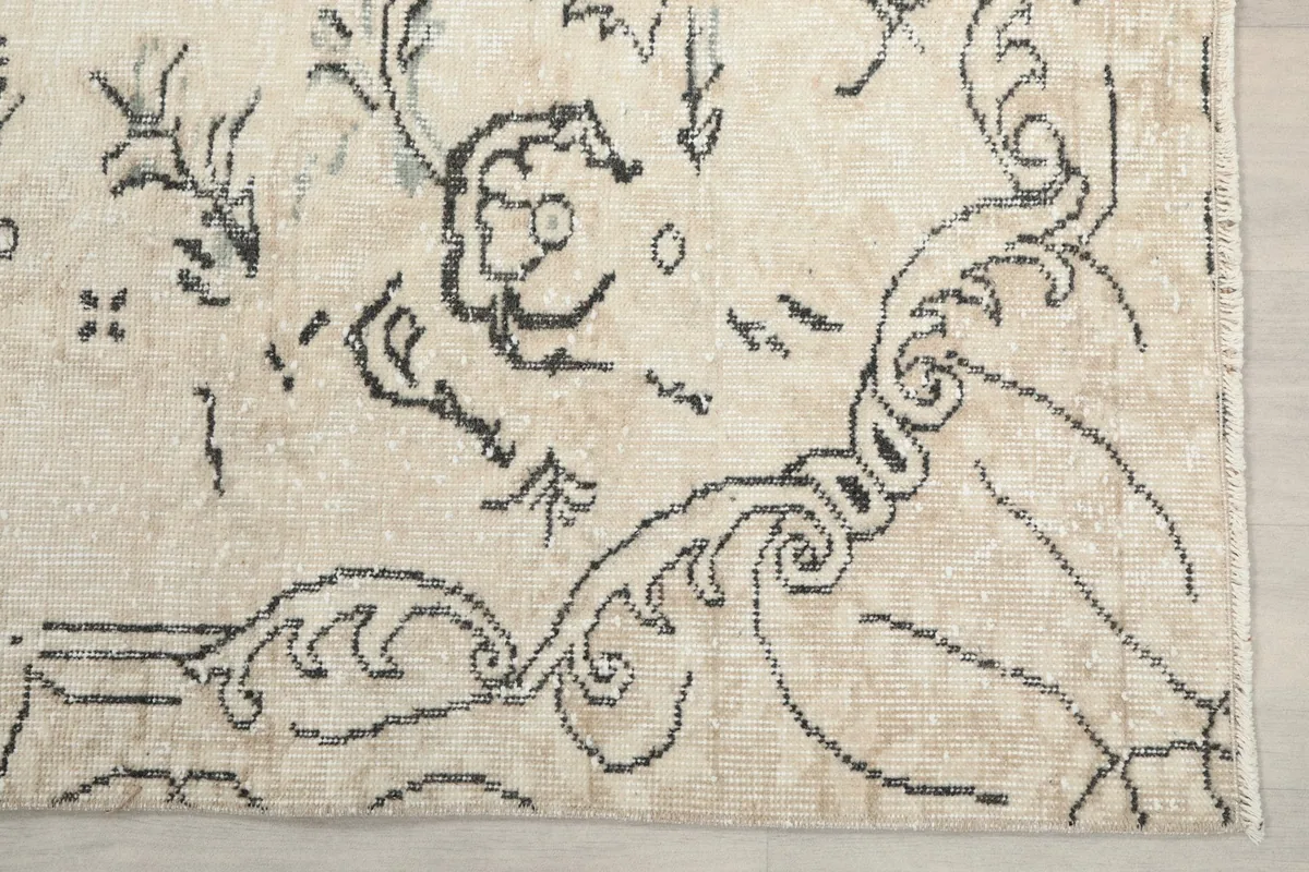 Detailed view of the charcoal scrollwork and floral elements on the rug's ivory border.