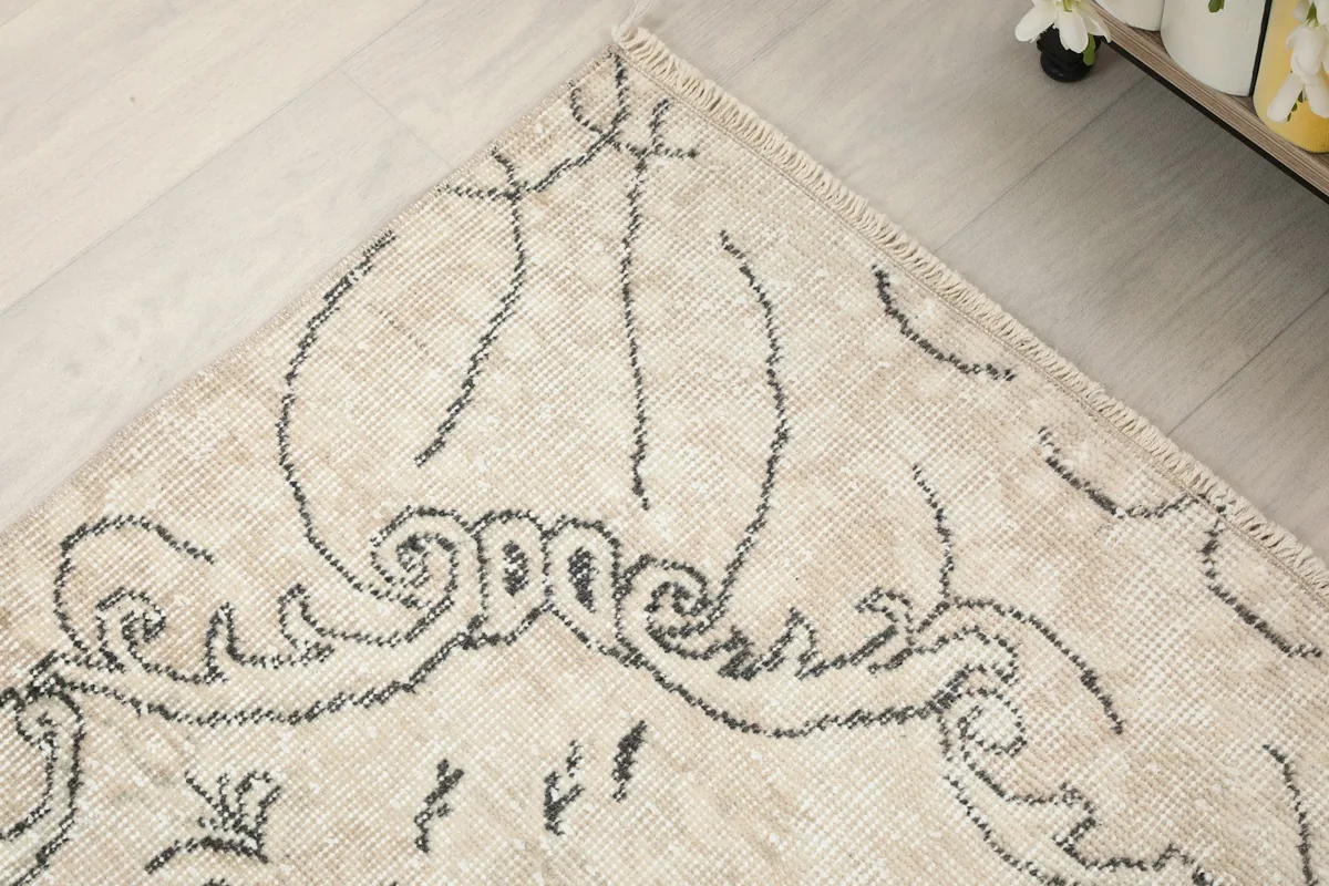 Corner detail of the rug's border, featuring intricate charcoal lines and patterns on the ivory background.