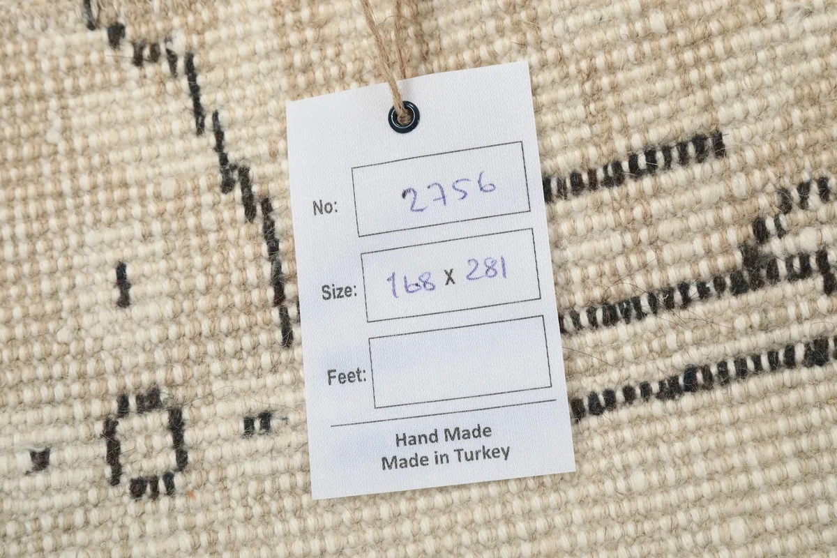 Close-up of the rug's cotton foundation and hand-knotted backing, with a product tag showing size.