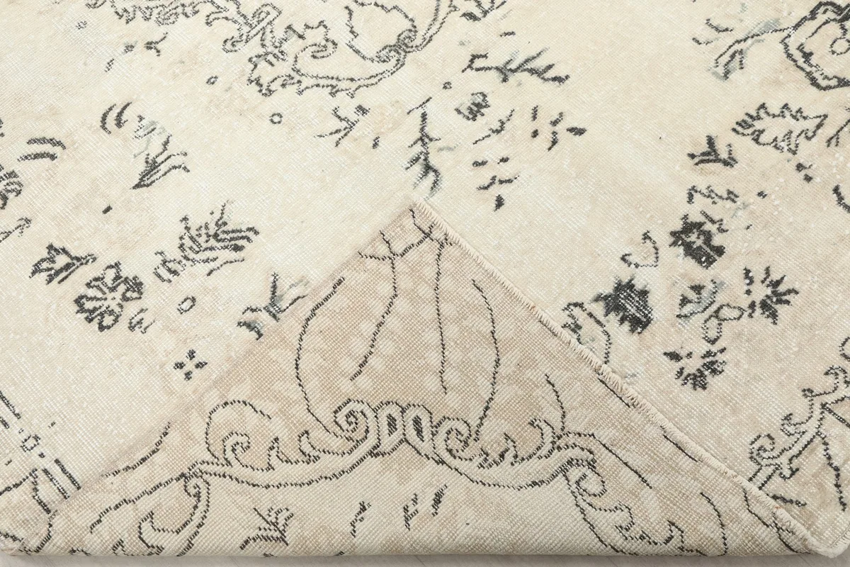 Folded corner of the rug, revealing the soft texture of the wool pile and the hand-knotted construction.