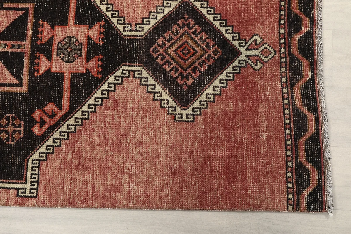 Detailed view of the rug's end, showing the rose field and black geometric patterns