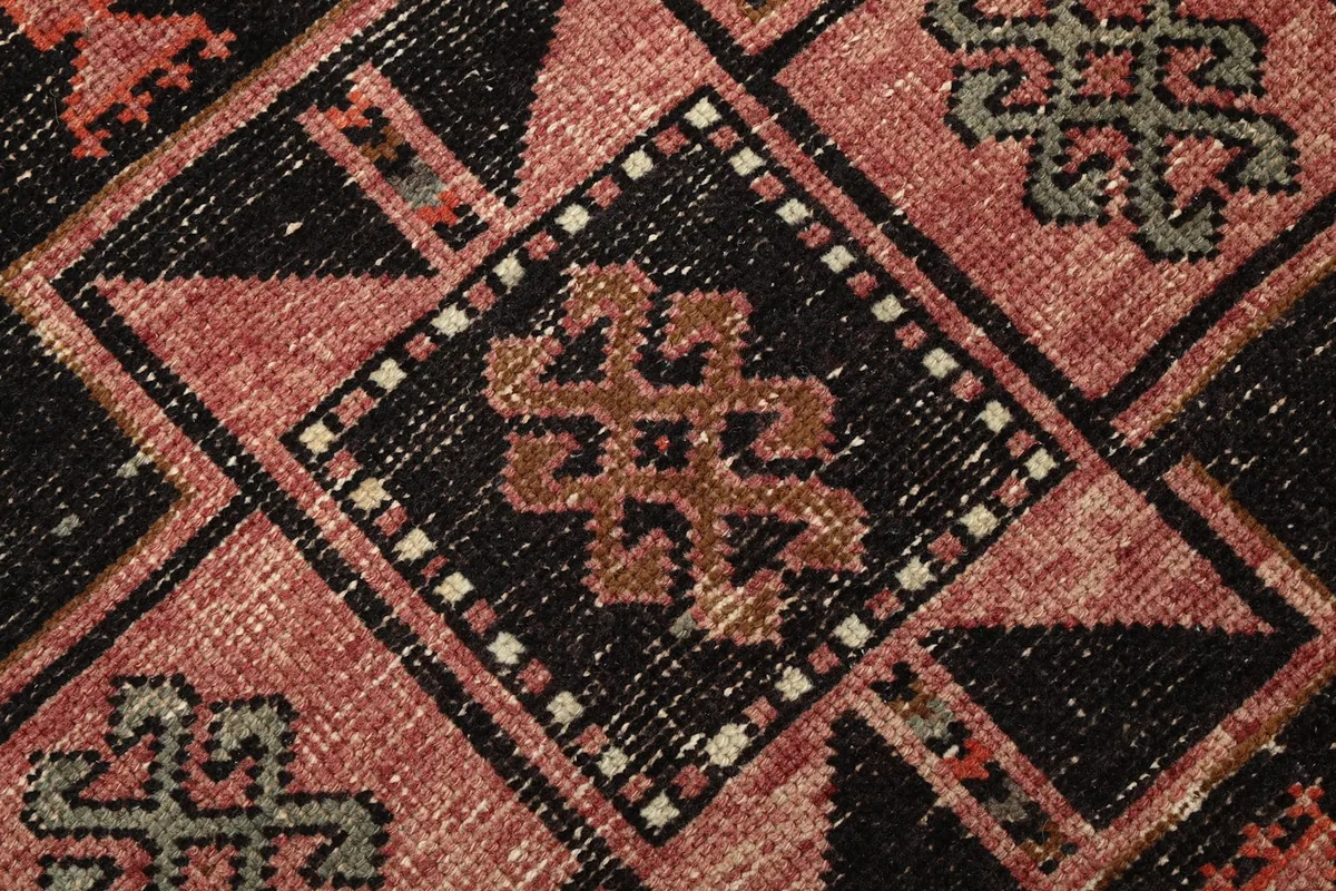 Macro detail of the hand-knotted wool pile and a central tribal motif in black and rust