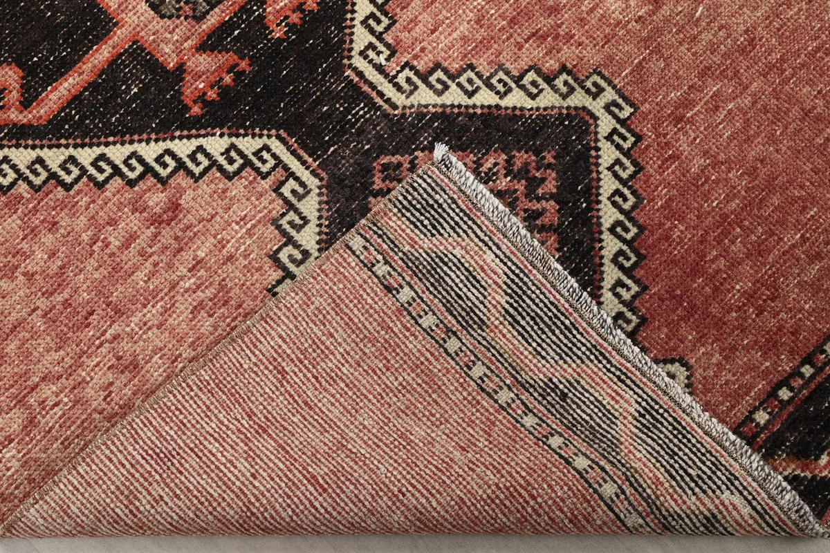 Folded corner showing the back of the rug, revealing the cotton foundation and knotting