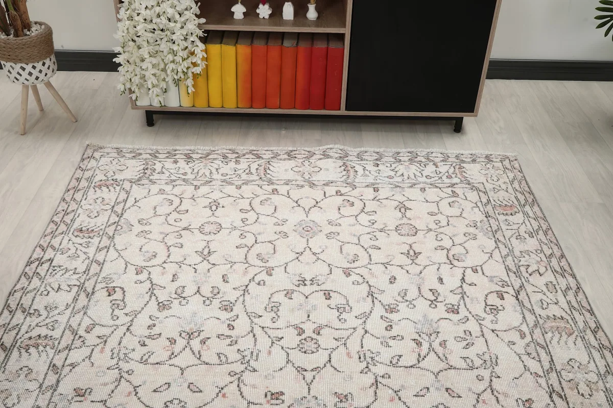 Overhead view of the vintage rug in a living room, emphasizing the central floral design and border details.