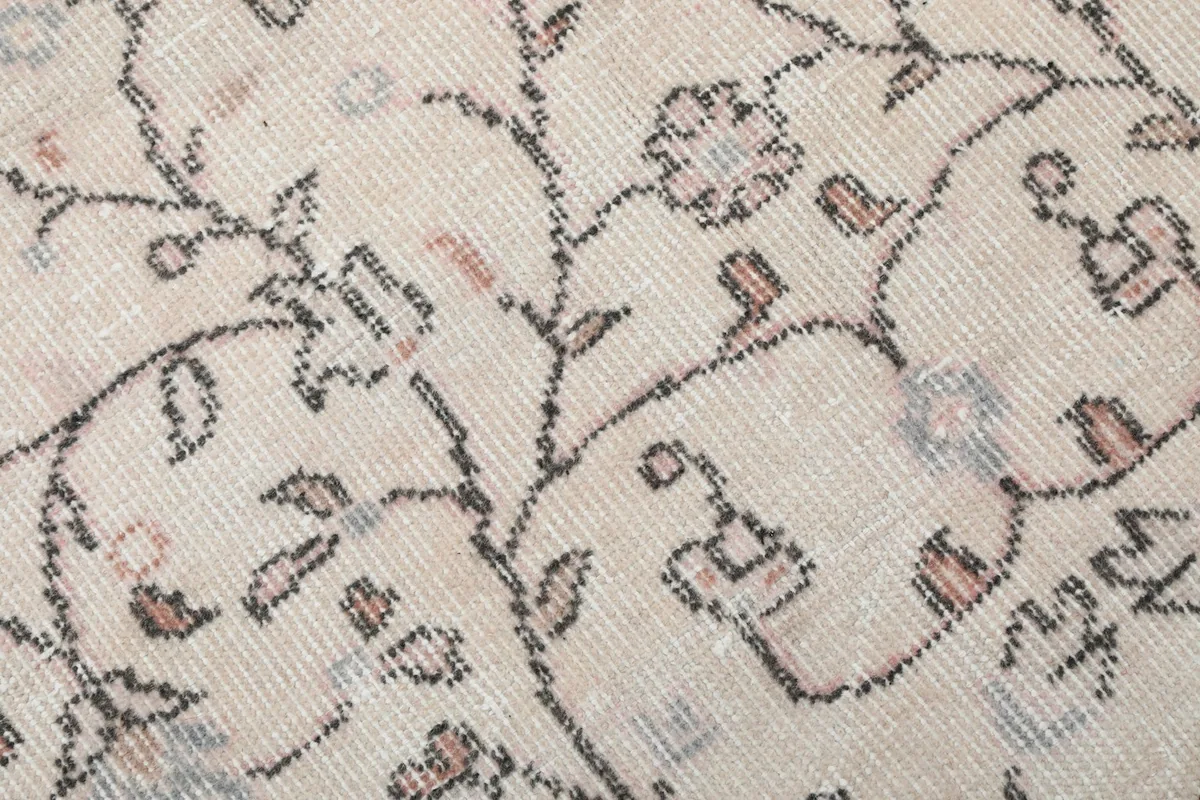 Close-up of the hand-knotted wool pile, showing the cream background with rose and gray floral details and low pile.