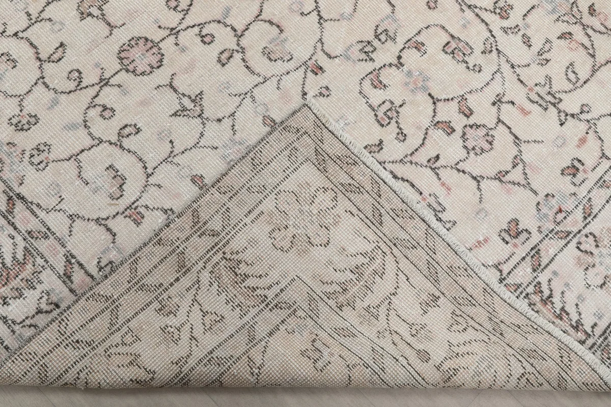 View of the backside of a corner of the rug, revealing the hand-knotted cotton foundation and the reverse of the pattern.