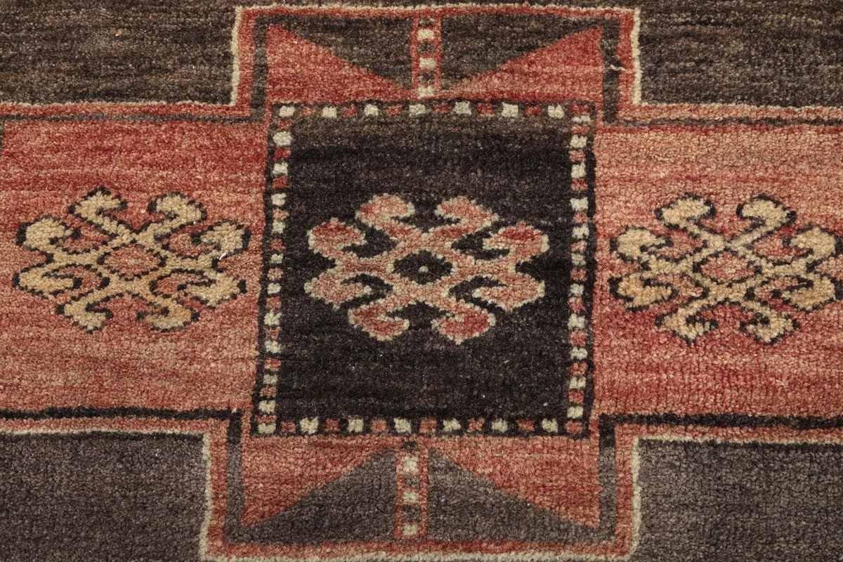 Detailed view of the intricate tribal patterns within the central medallions of the rug