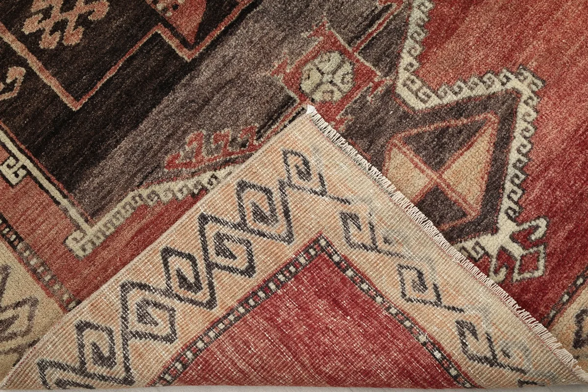 Close-up showing the low pile and hand-knotted construction of the rust and brown rug