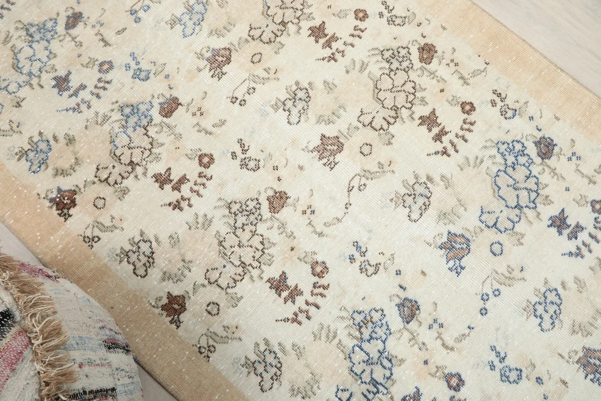 Angled view showcasing the overall faded floral design and texture of the cream wool pile
