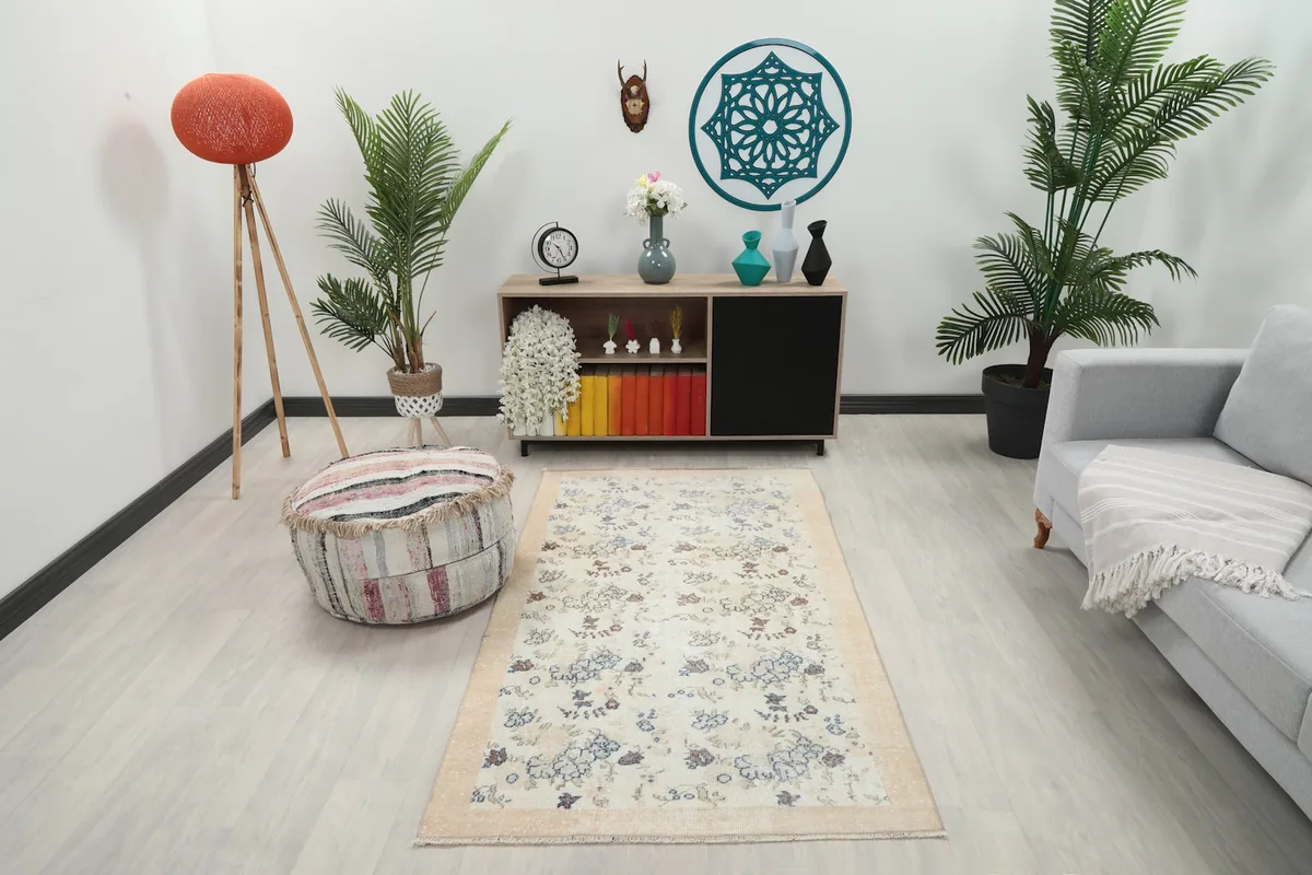 Cream floral rug placed in a modern living room setting with light furniture and plants
