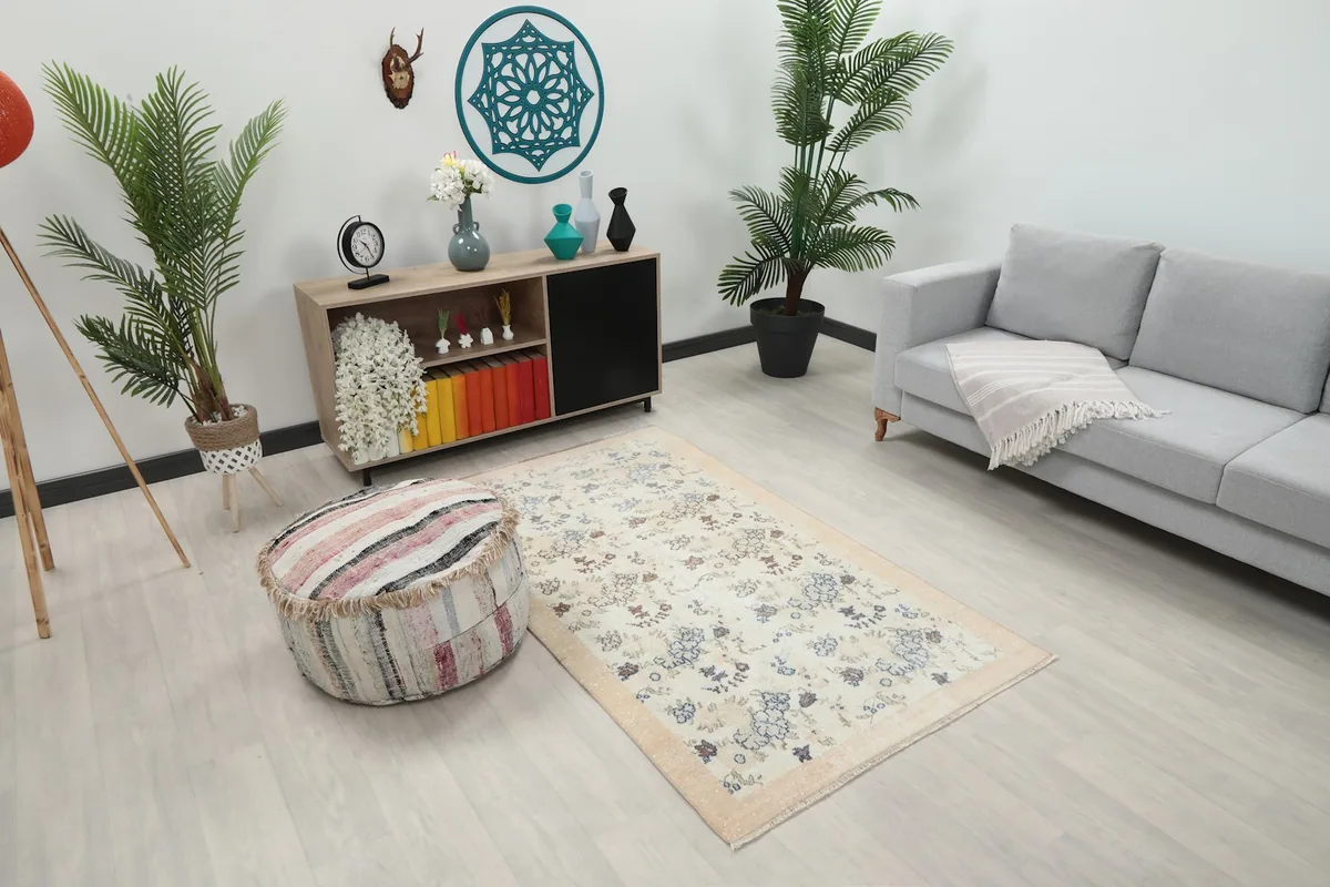 Overhead view of the vintage cream rug in a living space, showing its size relative to a sofa and ottoman