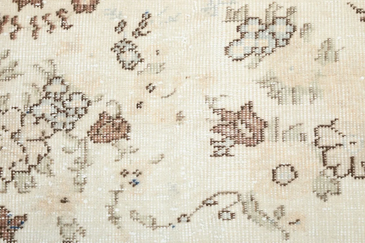 Detailed close-up of the faded blue and rust geometric floral motifs on the cream field
