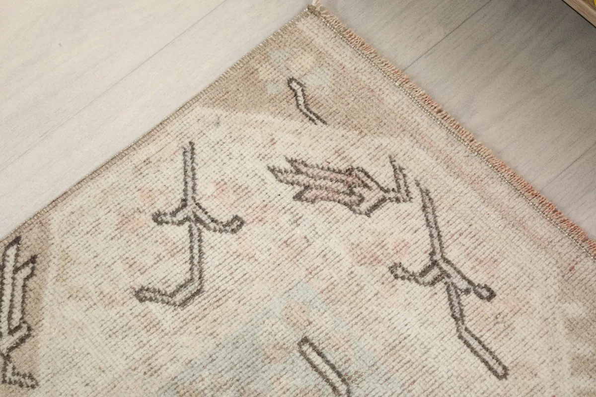 Close-up of the rug's edge and subtle tan border, highlighting the hand-knotted texture.