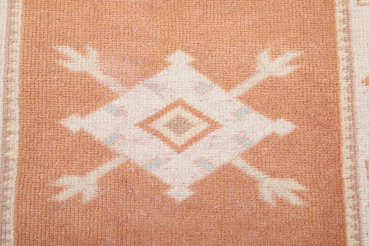 Macro detail of one of the main geometric motifs in the center of the orange runner rug.