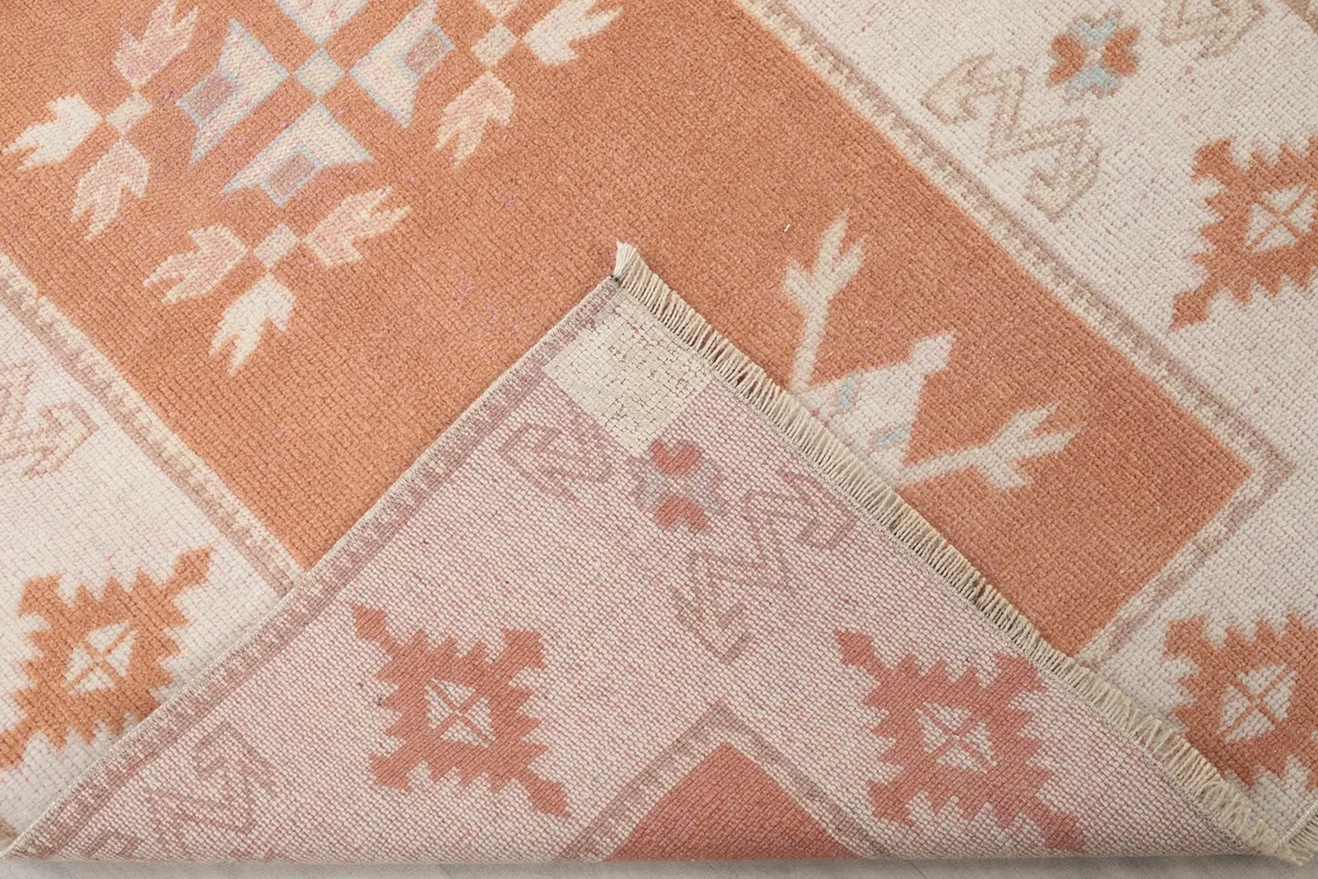 View of the back of the hand-knotted wool rug, partially folded to show the cotton foundation.