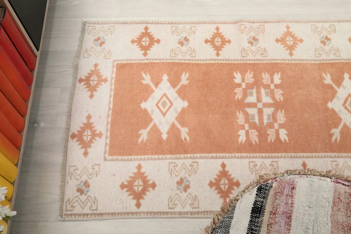 Overhead close-up of a section of the runner rug, showing the repeating orange and beige geometric patterns.