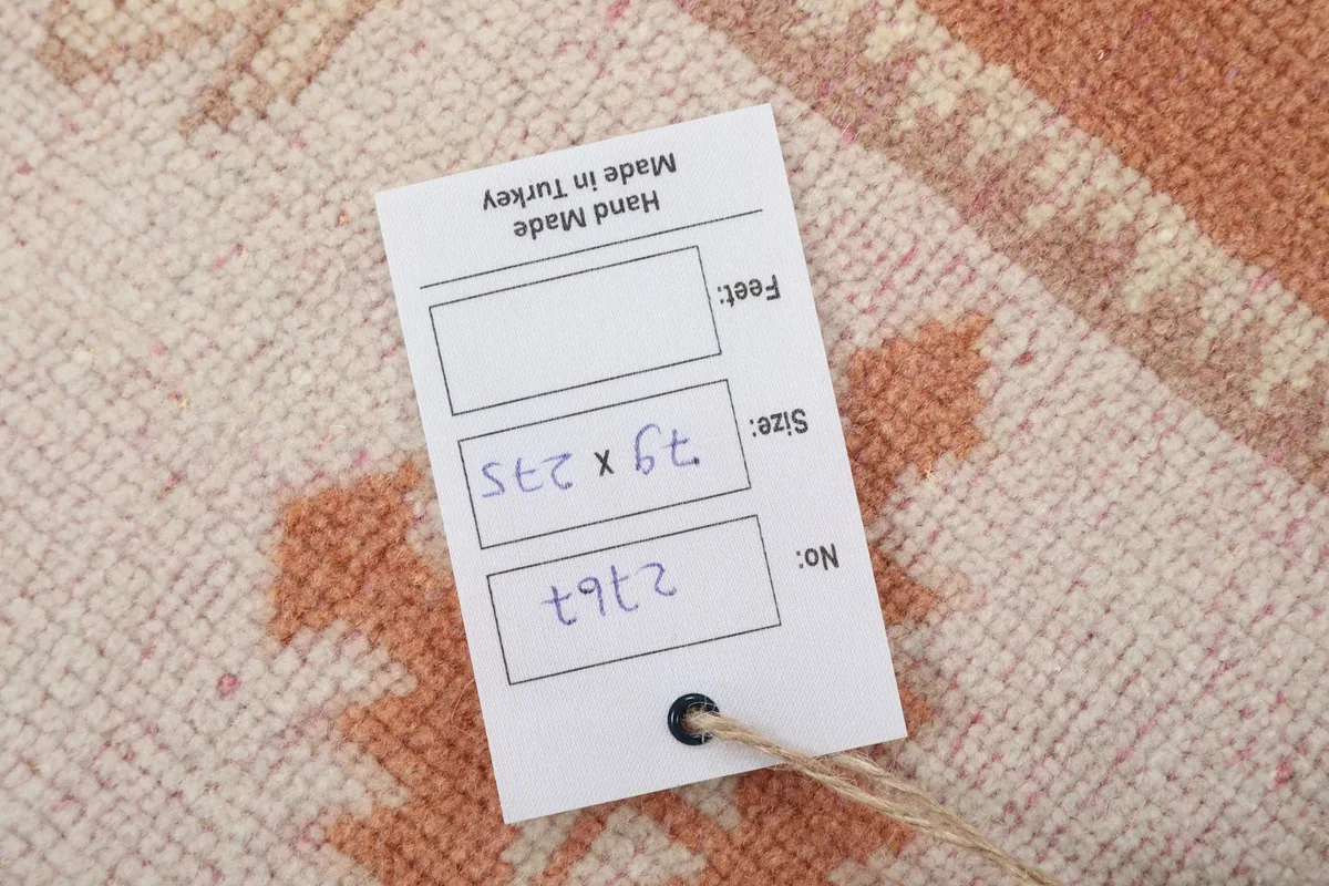 Close-up of the rug's label, displaying its dimensions in centimeters and feet, and origin information.