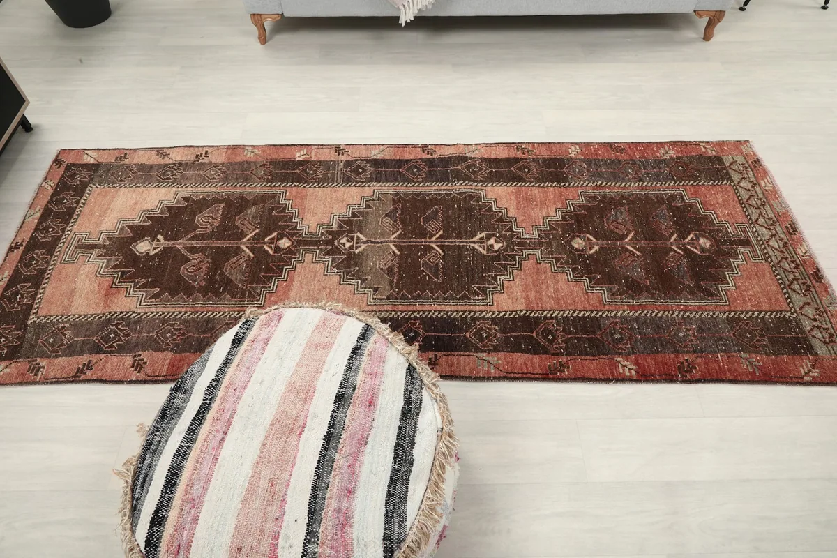 Top-down view of the runner rug next to a striped pouf, showing its full length in a room
