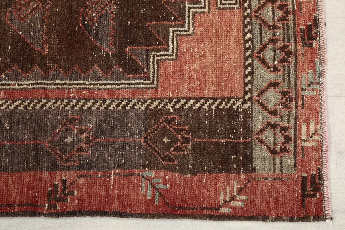 Detail of the rug's corner with geometric border patterns and color variations