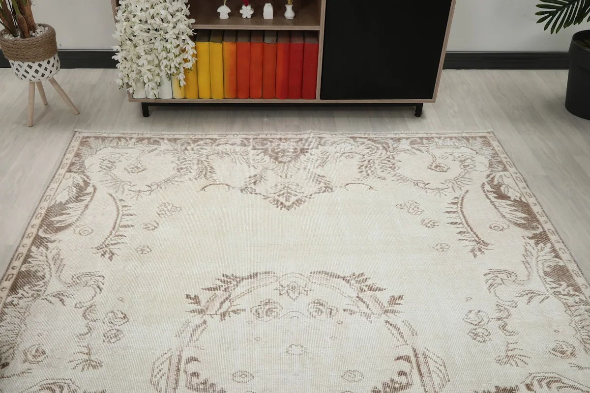 View of one end of the ivory beige rug, showcasing the faded ornamental patterns