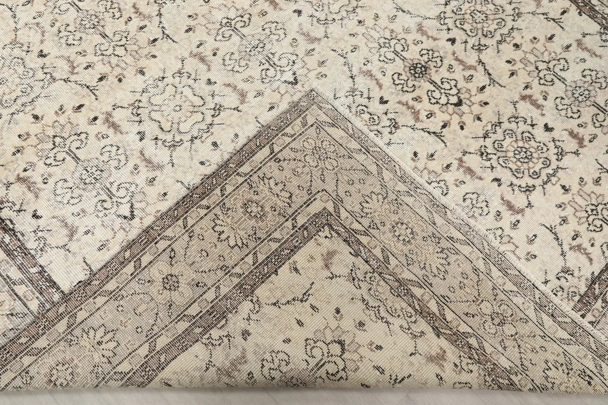 Folded back corner revealing the hand-knotted wool pile and cotton foundation of the rug