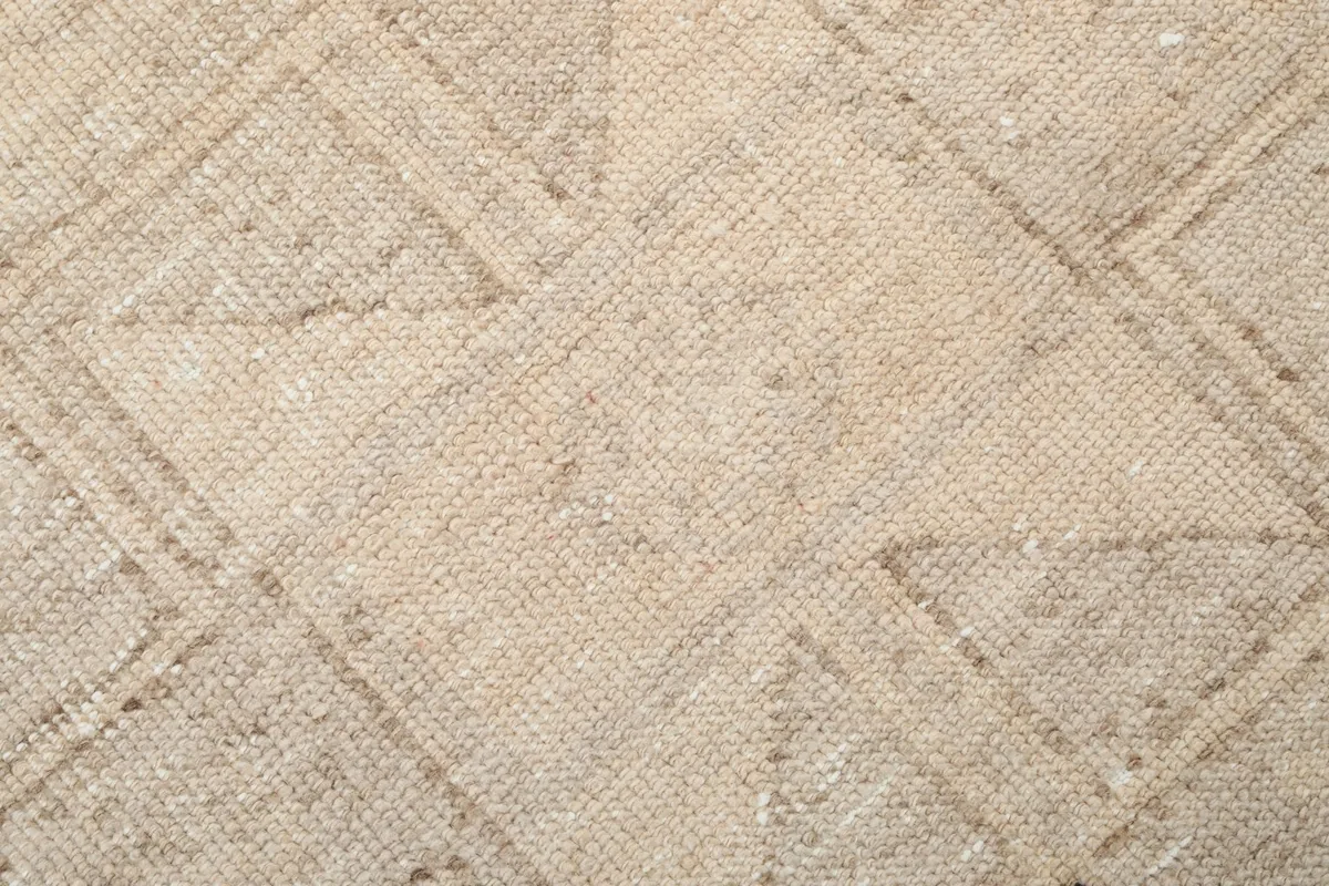 Texture and pattern detail of the hand-knotted wool pile, showing faded geometric lines.