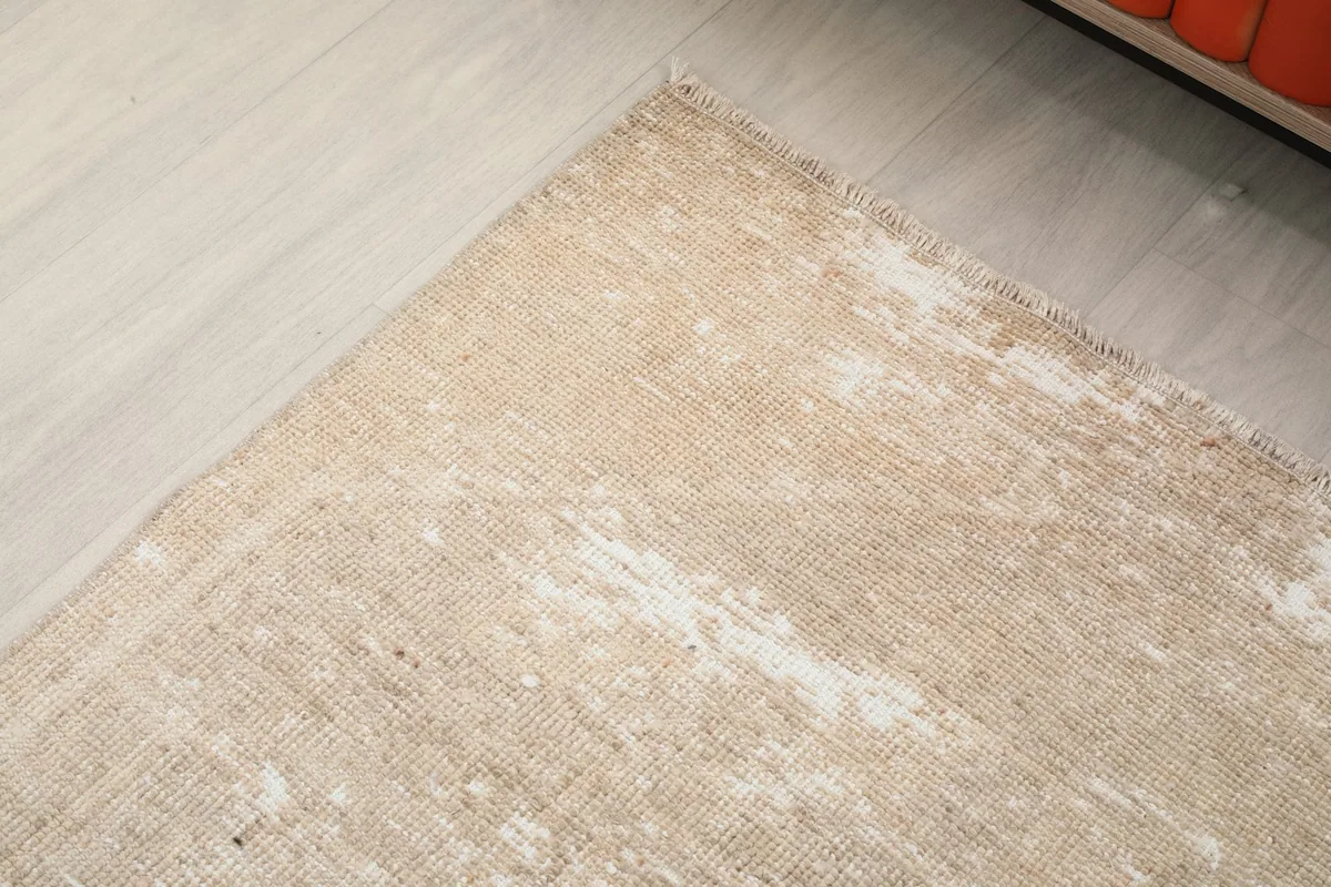Close-up of the low wool pile and distressed areas of the beige vintage runner rug.