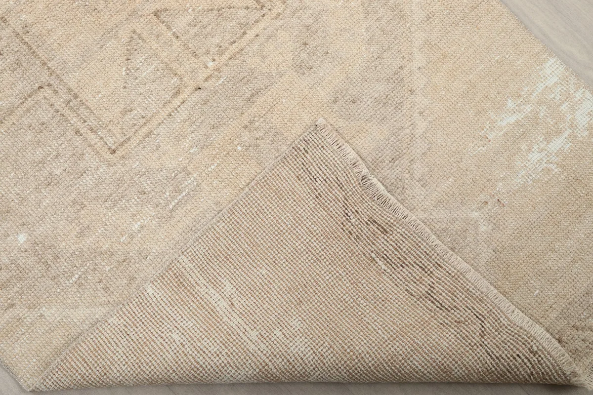 Corner of the rug folded back to show the hand-knotted cotton foundation and wool pile.