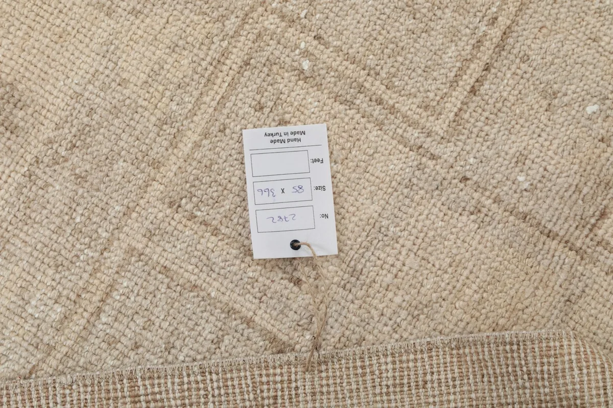 Close-up of the rug's surface with a measurement tag, showing the texture and faded details.