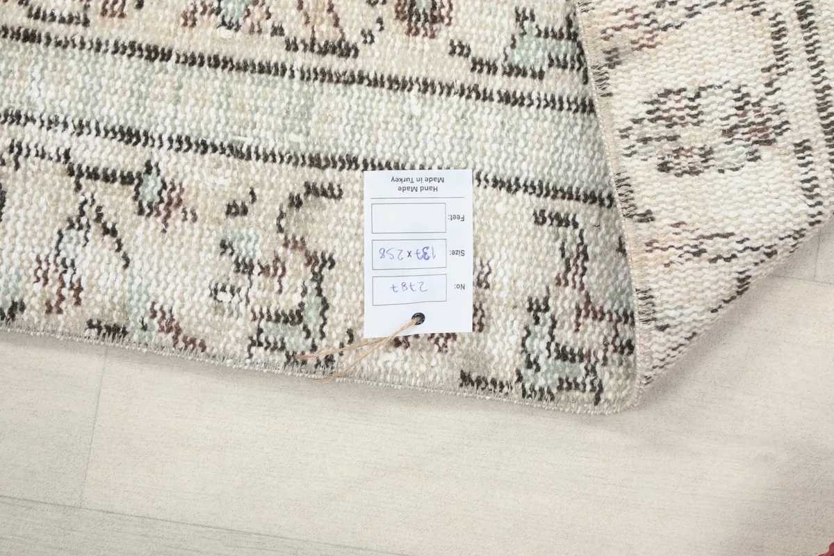 Close-up of the rug's back, showing the hand-knotted construction and a product tag