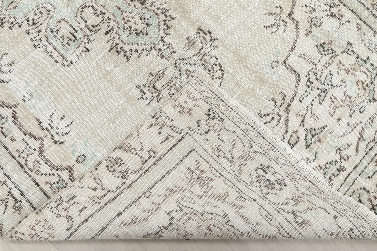 Corner of the rug folded back to show the cotton foundation and reverse side of the wool pile