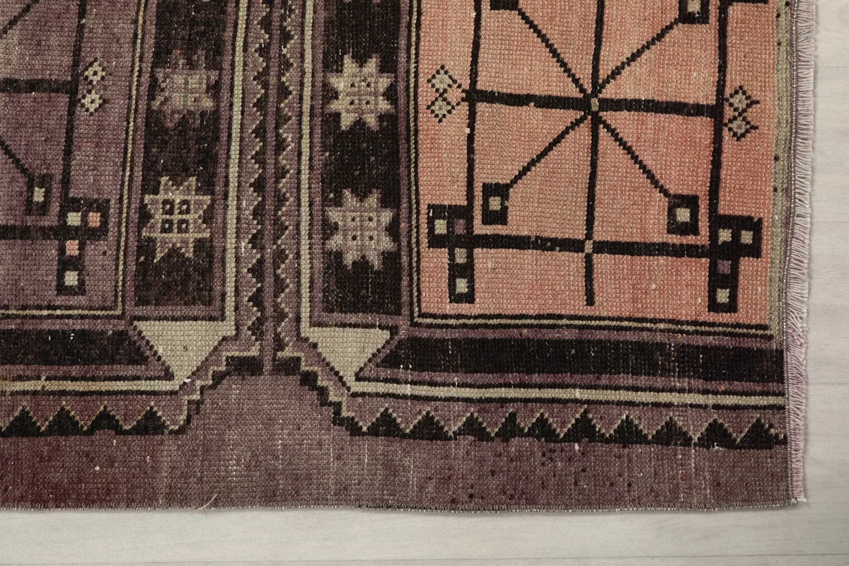 Detailed view of the rug's end, showing the rose geometric pattern and border