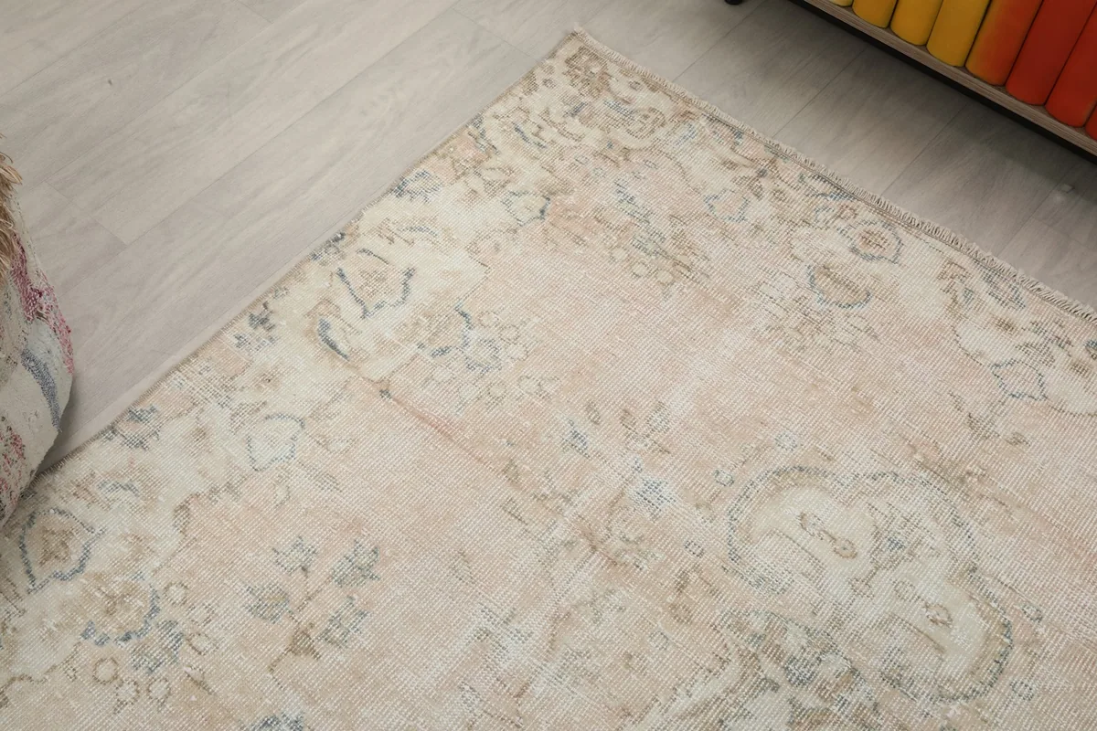 Angled view of a rug corner, showcasing the border design and the faded aesthetic of the wool.