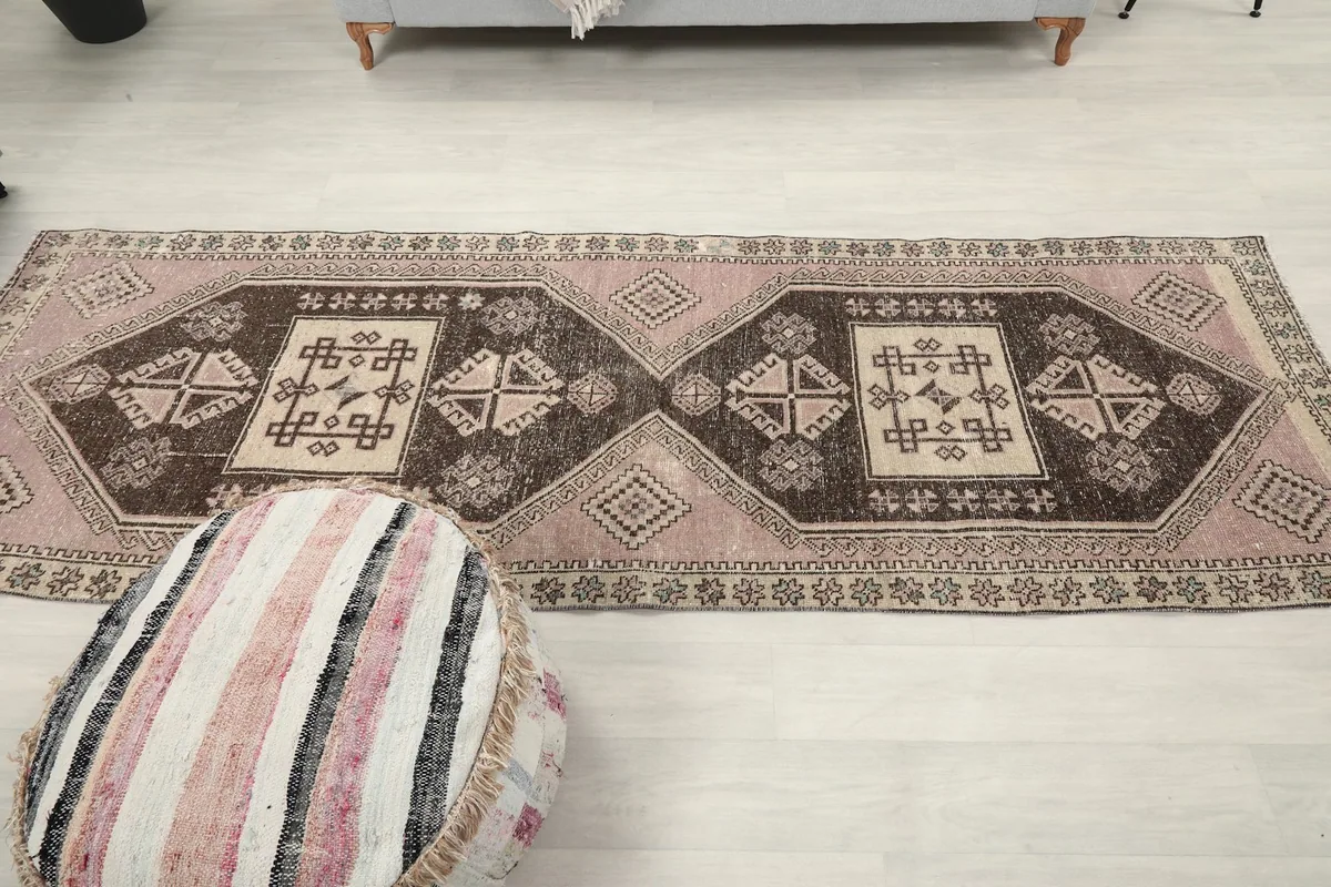 Wide room shot of the runner rug, emphasizing its length and how it anchors the space between a sofa and an ottoman.