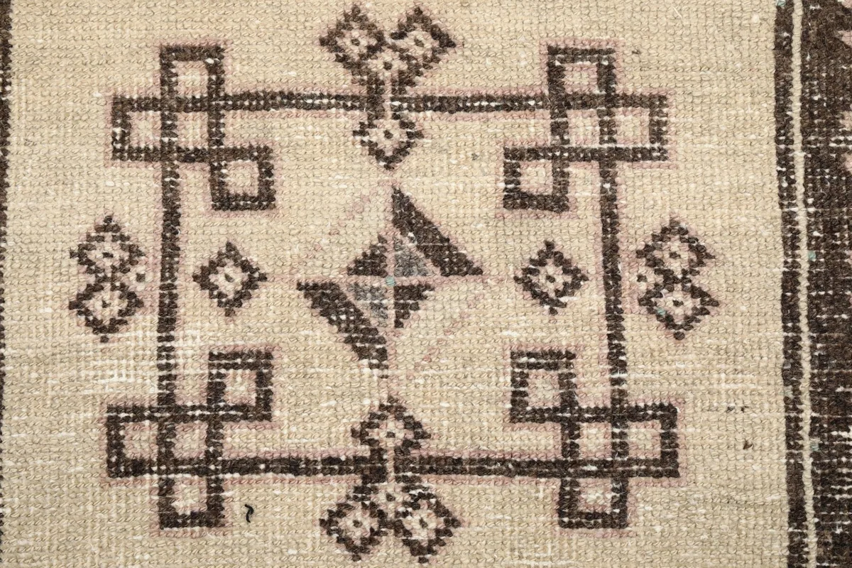 Close-up of a central beige medallion with intricate brown geometric knotwork and subtle color variations.
