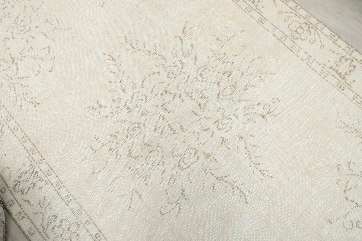 Close-up of the central floral and leafy motifs on the ivory field of the rug