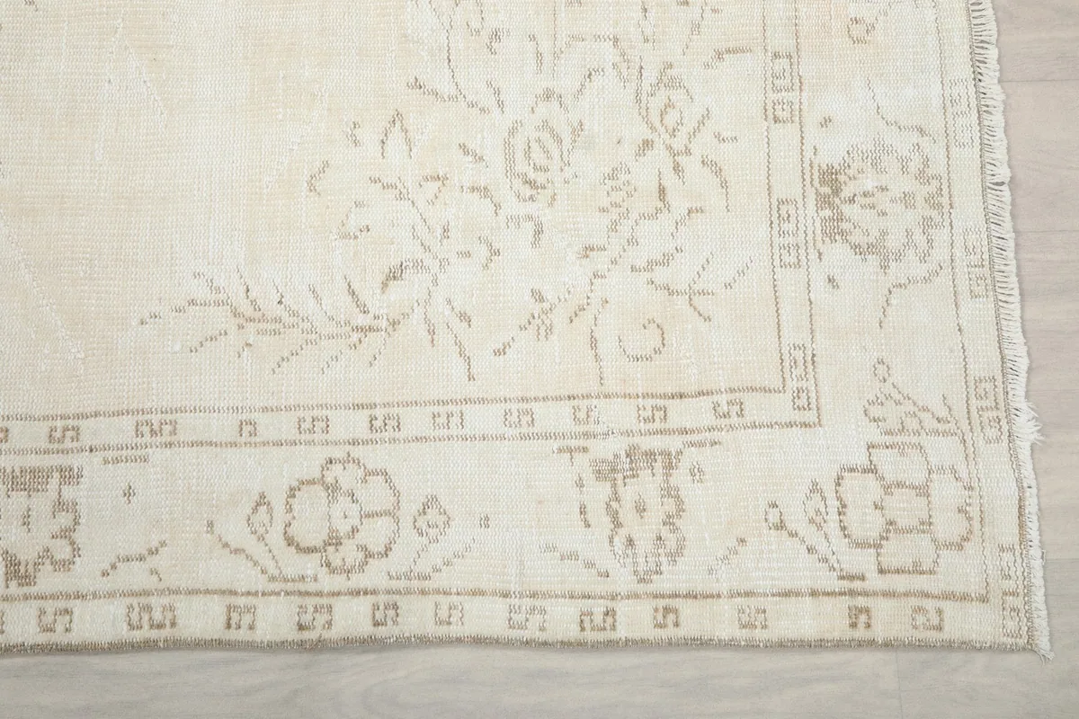 Detail of the rug's beige geometric border and corner floral motifs