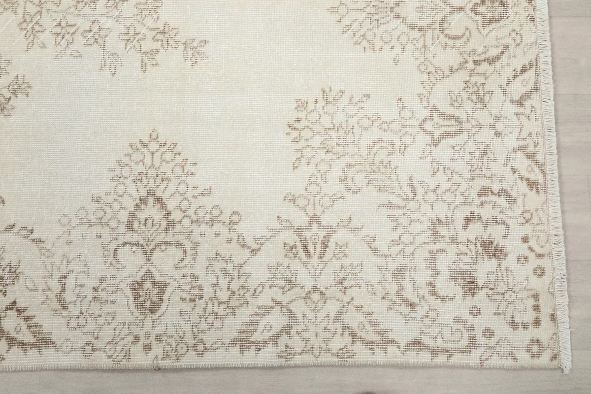 Detail of the rug's border pattern in beige against an ivory background