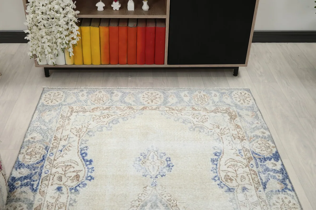 Overhead view focusing on the upper half of the rug, highlighting the ivory field and blue accents.