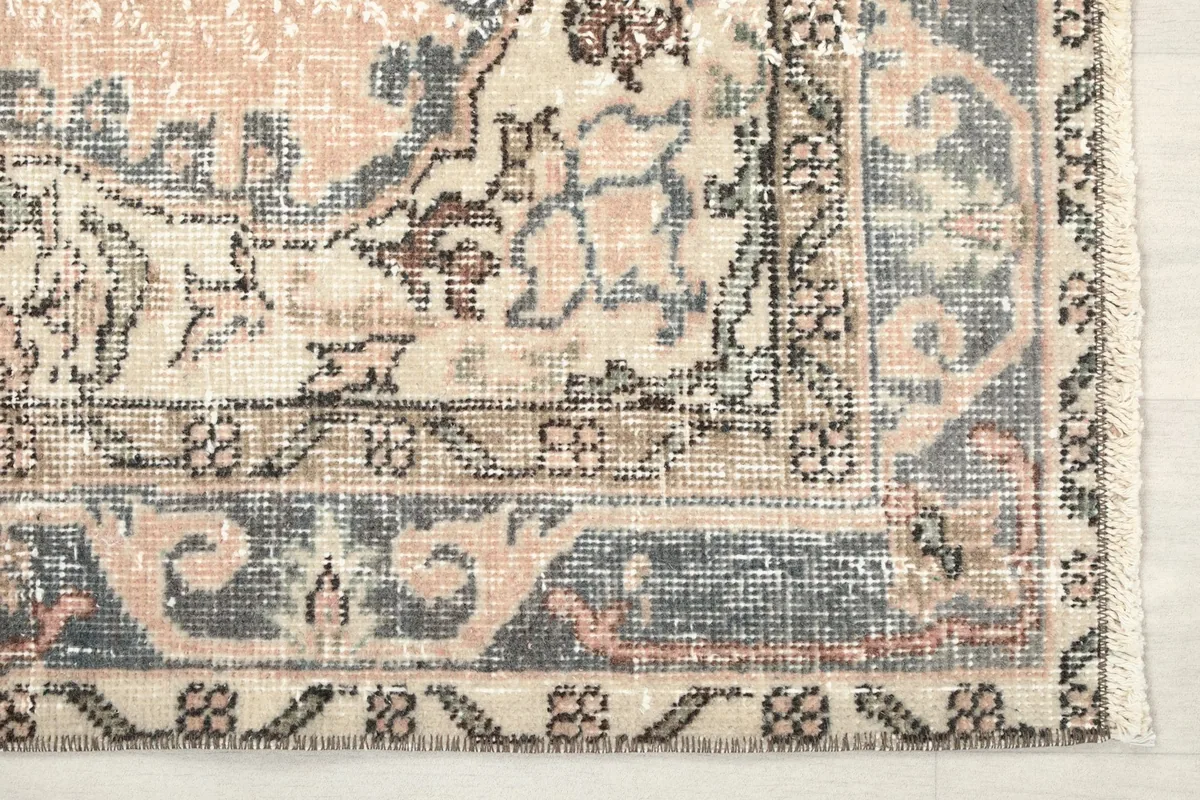 Detailed view of the rug's corner, showcasing the intricate border patterns in gray and beige