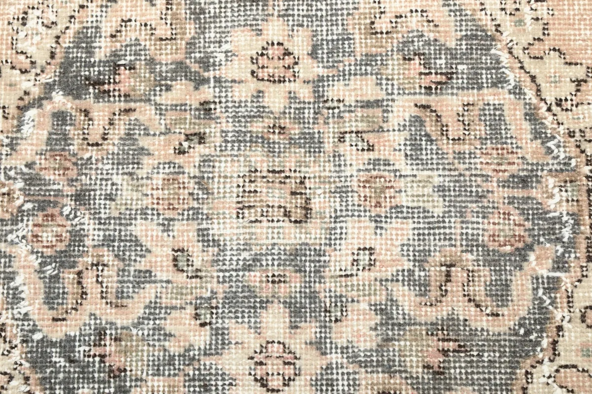 Texture detail of the low pile wool surface, highlighting the faded colors and hand-knotted weave