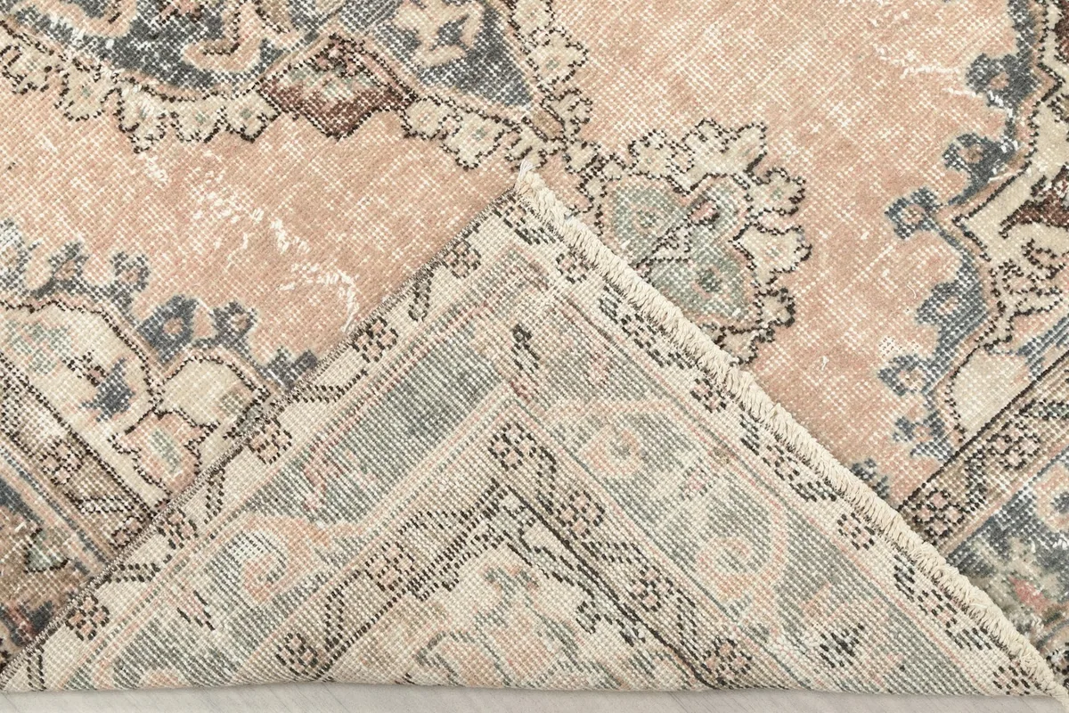 Corner of the rug folded to reveal the cotton foundation and reverse side of the hand-knotted wool pile