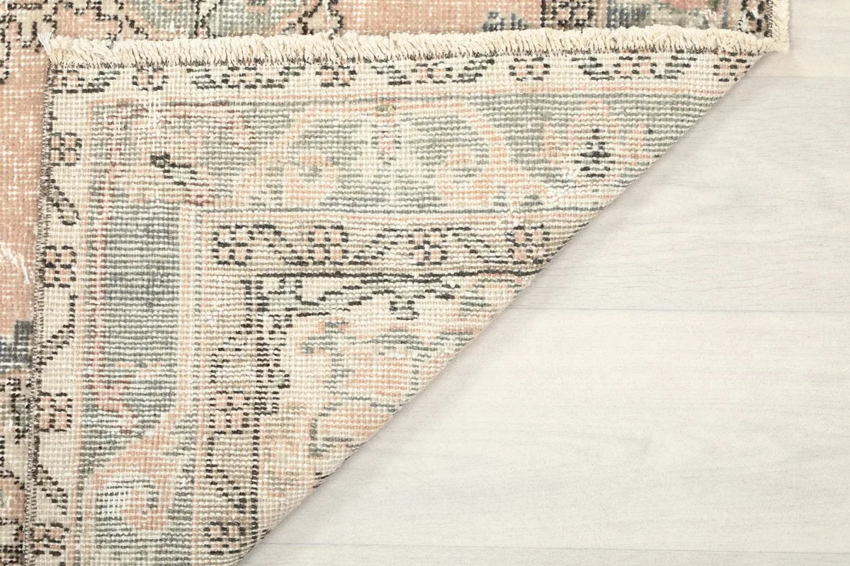 View of the rug's fringe and a folded corner, showing the back and the edge craftsmanship