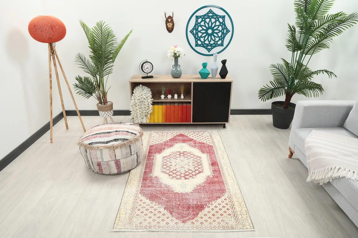 Rose and ivory rug displayed in a living room setting with a sofa and pouf