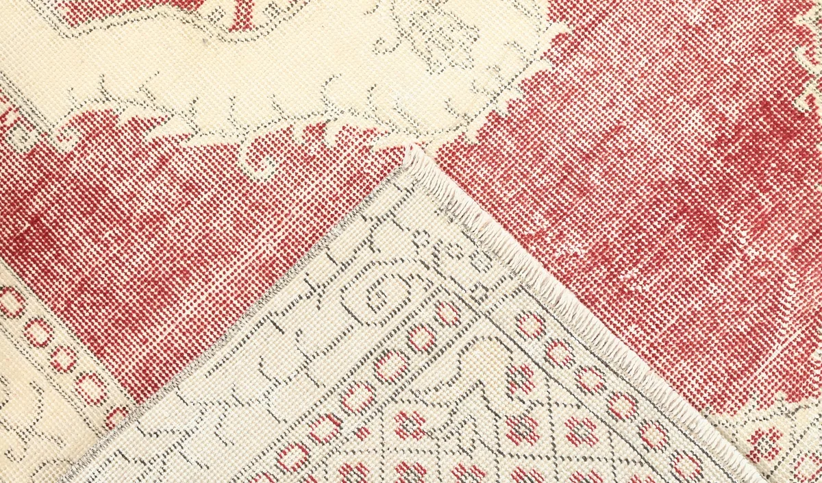 Corner of the rug folded to reveal the cotton foundation and knotting