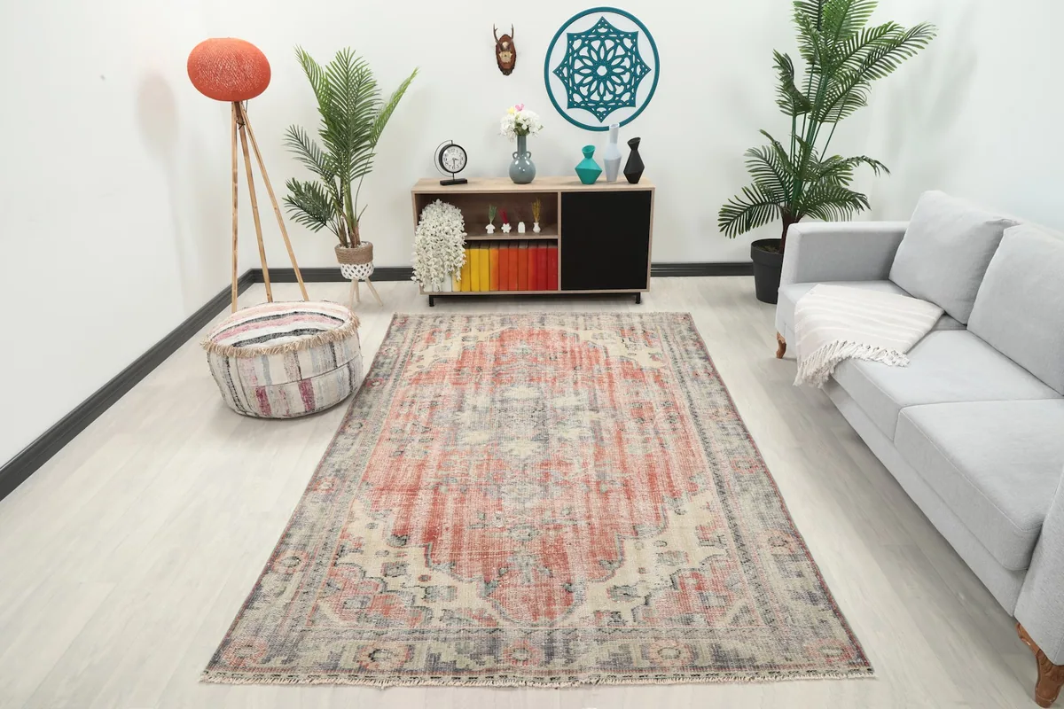 Rose and gray vintage Anatolian rug displayed in a living room setting with a sofa and plants