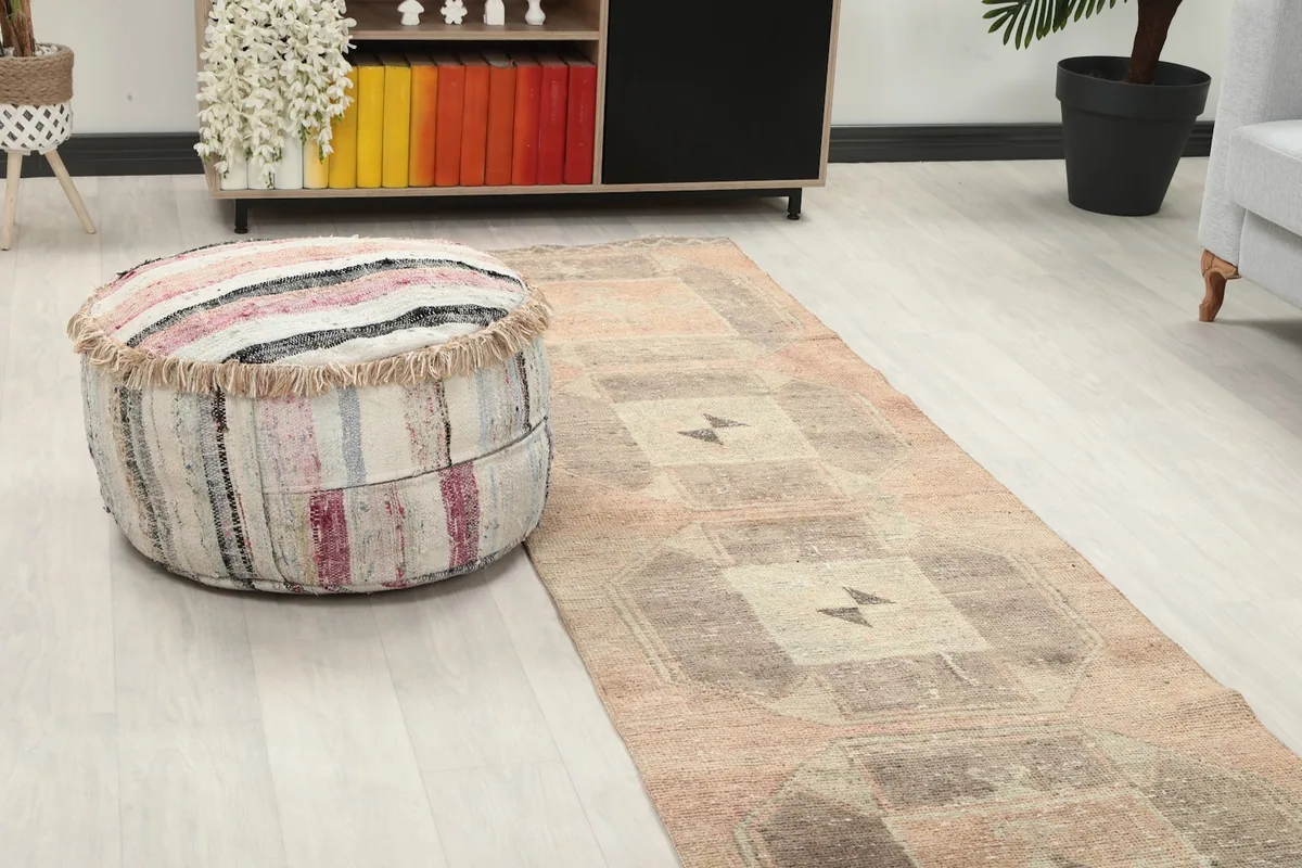 Close-up angle of the rust and gray runner rug with a striped ottoman