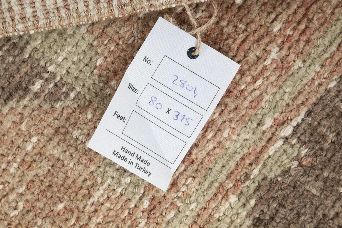 Close-up of the product tag indicating 'Hand Made Made in Turkey' and rug dimensions